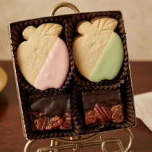 Box of assorted cookies with a decorative bow on a wooden surface
