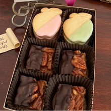 Gift box with a pink ribbon and bow on a wooden surface with books and apples in the background.
