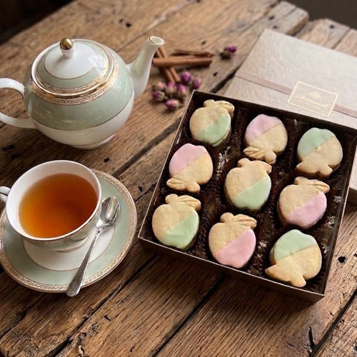 Tea set with a teapot, cup, and shortbread cookies on a wooden table.