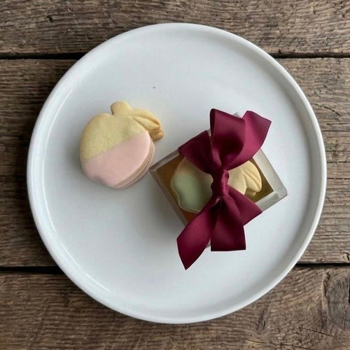 Two small pshortbread favours on a white plate with a wooden background