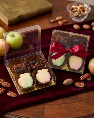 Two gift boxes with pastries and a red ribbon on a wooden surface with apples and nuts.